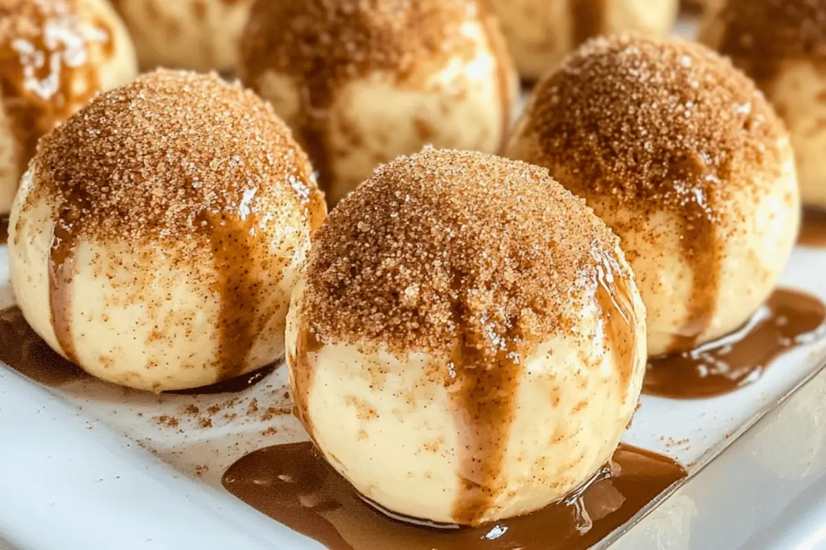 Creamy no-bake pumpkin pie cheesecake balls coated with graham cracker crumbs and white chocolate, served as a delicious fall dessert